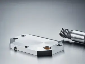 Präzisionsgefräste Aluminiumbauteile auf Stahloberfläche mit CNC-Fräser, sichtbare Werkzeugspuren, diffuses Industrielicht.