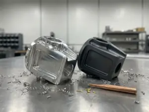 Poliertes Aluminiumteil neben matt-eloxiertem Gegenstück auf Stahlwerkbank, umgeben von feinen Metallspänen.