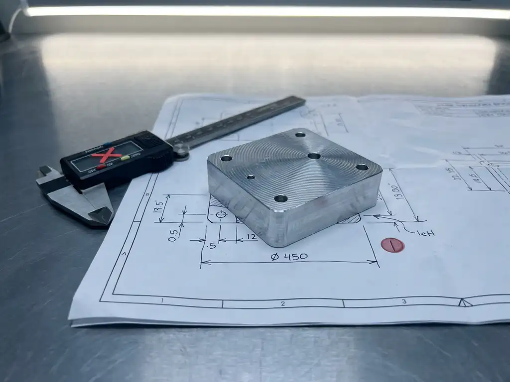 Gefrästes Aluminiumteil mit Werkzeugspuren auf technischer Zeichnung, daneben ein rot markiertes Messschieber-Maß als Ausschuss-Kennzeichnung.