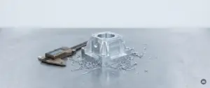 Gefräste Aluminiumkomponente auf Stahlwerkbank neben kalibrierten Messschiebern, umgeben von feinen Metallspänen, Draufsicht.